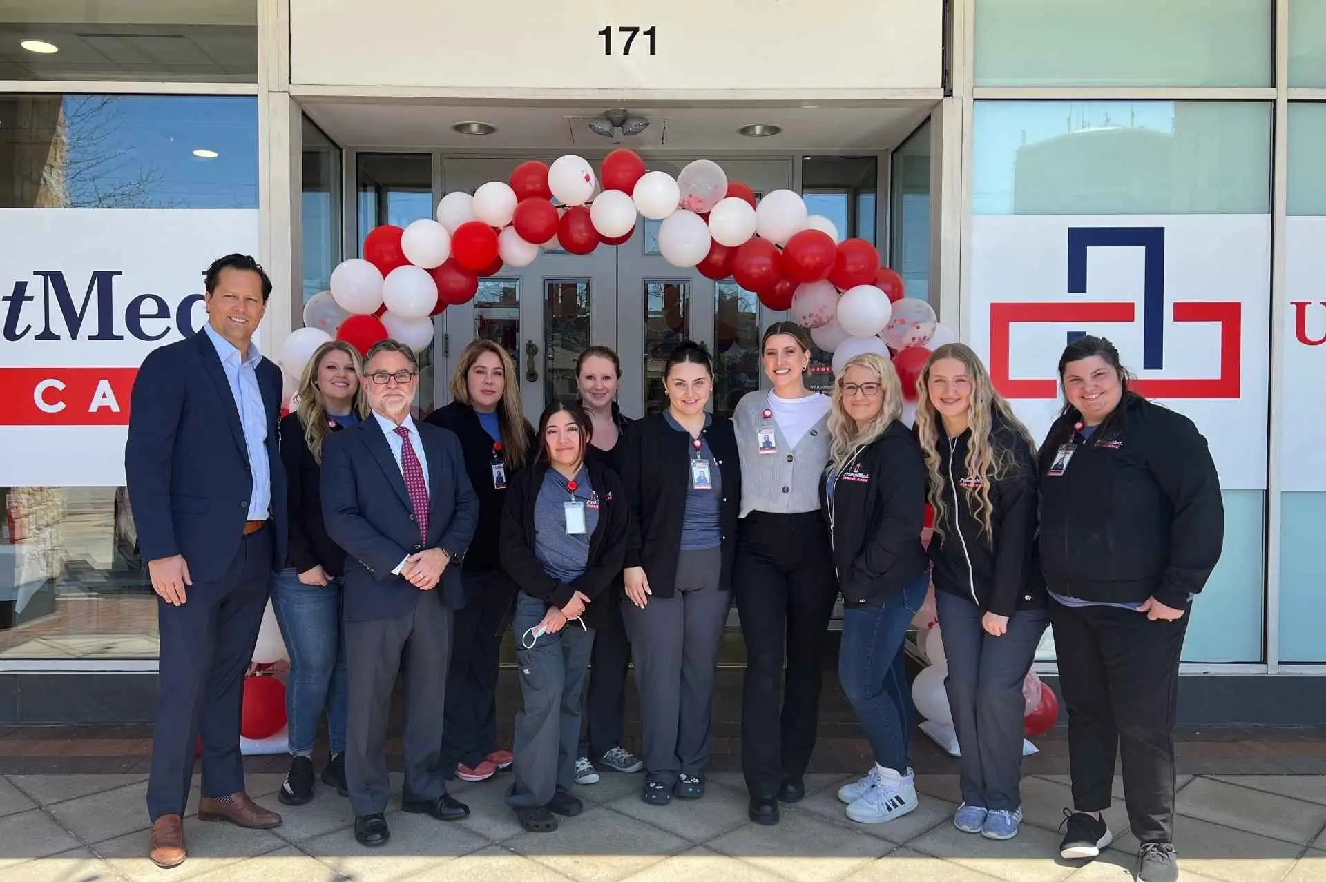 Group of medical professionals celebrating the opening of the medical clinic under a balloon arch
