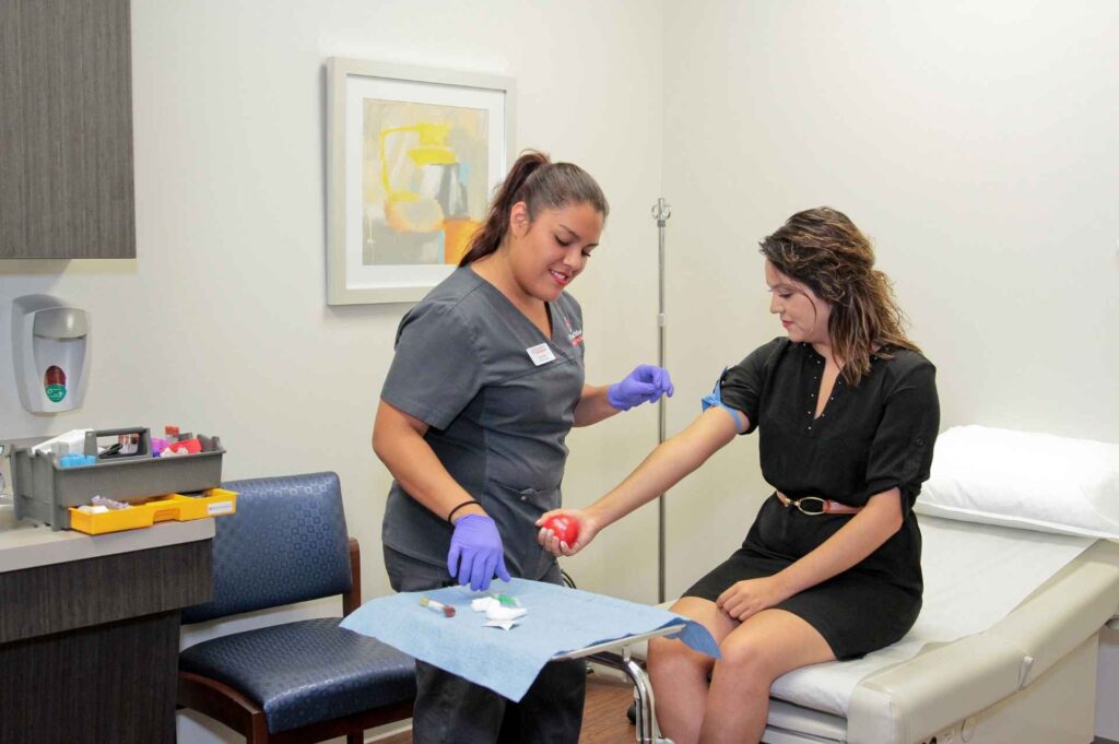 Profesional de la salud extrayendo sangre de un paciente en PromptMed Urgent Care